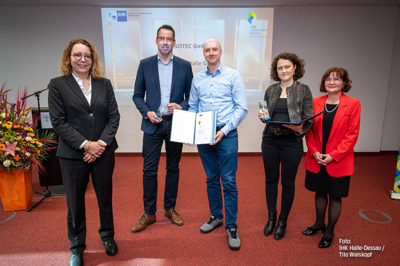 Fünf Personen stehen auf einem roten Teppich.