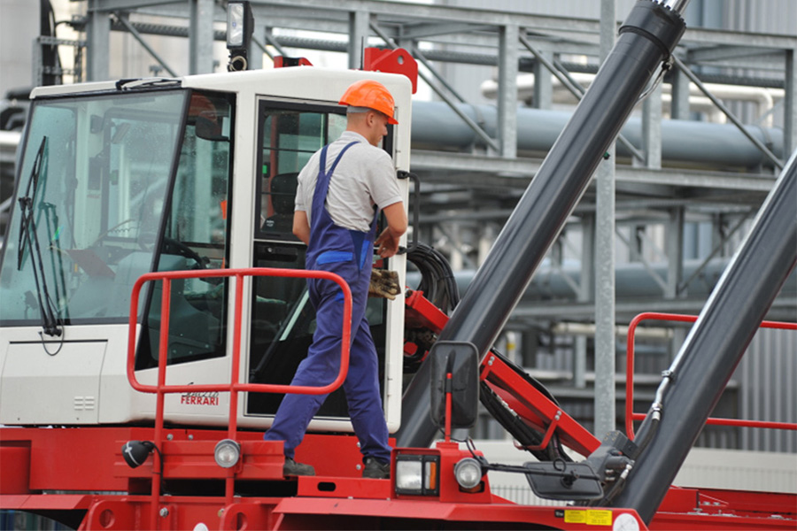 Mitarbeiter steht auf Reach Stacker.