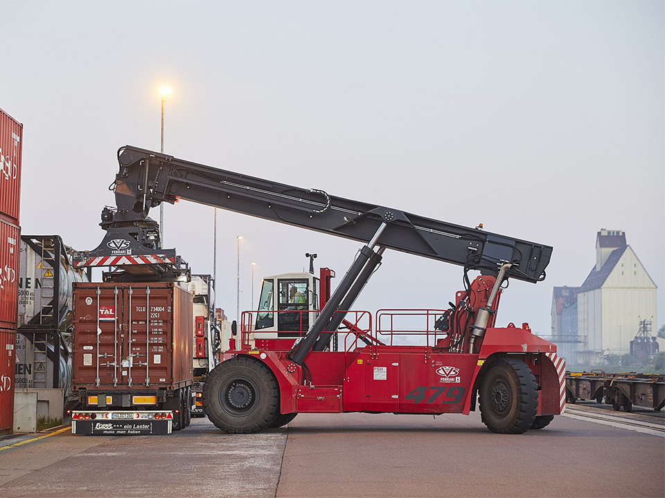 Roter Containerstapler hebt Container auf Lkw-Anhänger in einem Hafen 
