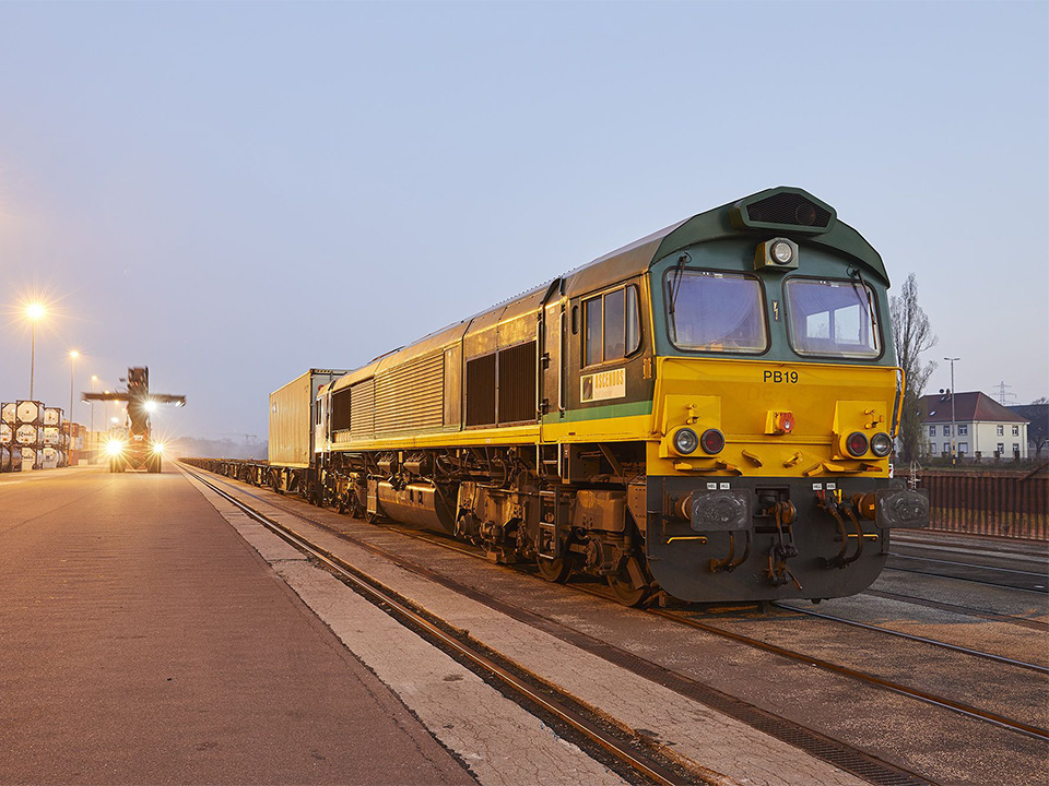 Reachstacker und Zug am Hafenbecken.